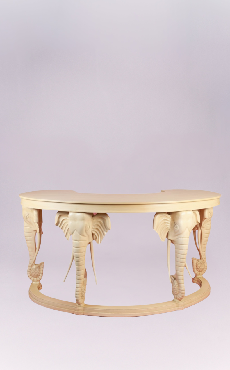 This extraordinary piece is a tribute to artisanal craftsmanship, featuring a distinctive kidney bean-shape that elegantly curves to invite conversation. The table is supported by exquisitely carved elephant legs, each a masterpiece of detail, complete with tusks and intricate adornments. Perfect as a unique console in an entryway, a luxurious vanity, or an unconventional coffee table, it promises to be a cherished focal point in any sophisticated interior.