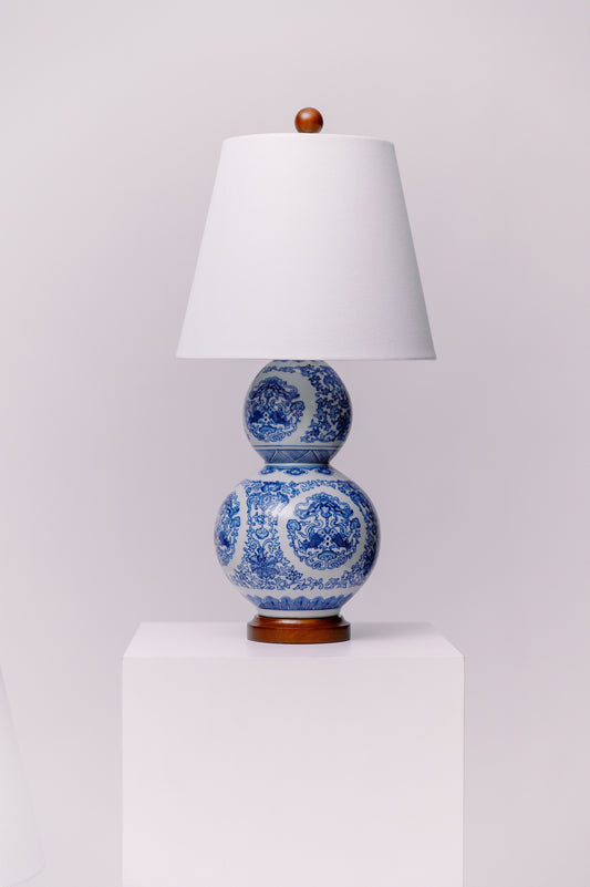 This pair of Ralph Lauren porcelain double gourd lamps features an intricate blue-and-white chinoiserie-inspired pattern on a classic silhouette. The bases are mounted on rich wood with brass-plated “Lauren” nameplates. Timeless in design and high in quality, these statement pieces add elegant symmetry to any traditional, coastal, or eclectic interior.  