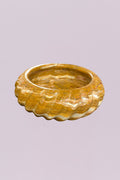 Make a statement with this hand-carved golden onyx marble bowl, featuring striking natural banding and a sculptural scalloped edge. The layered tones of warm amber, cream, and soft gold create a one-of-a-kind pattern, giving this piece depth and movement from every angle.