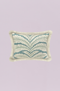 A charming rectangular pillow featuring a classic, repeating tropical leaf or frond pattern in soothing aqua and sage tones on a light neutral background. The piece is beautifully finished with a dense, natural ivory fringe, adding coastal texture and a relaxed, breezy feel.