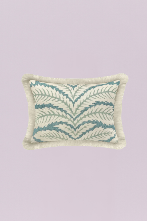 A charming rectangular pillow featuring a classic, repeating tropical leaf or frond pattern in soothing aqua and sage tones on a light neutral background. The piece is beautifully finished with a dense, natural ivory fringe, adding coastal texture and a relaxed, breezy feel.