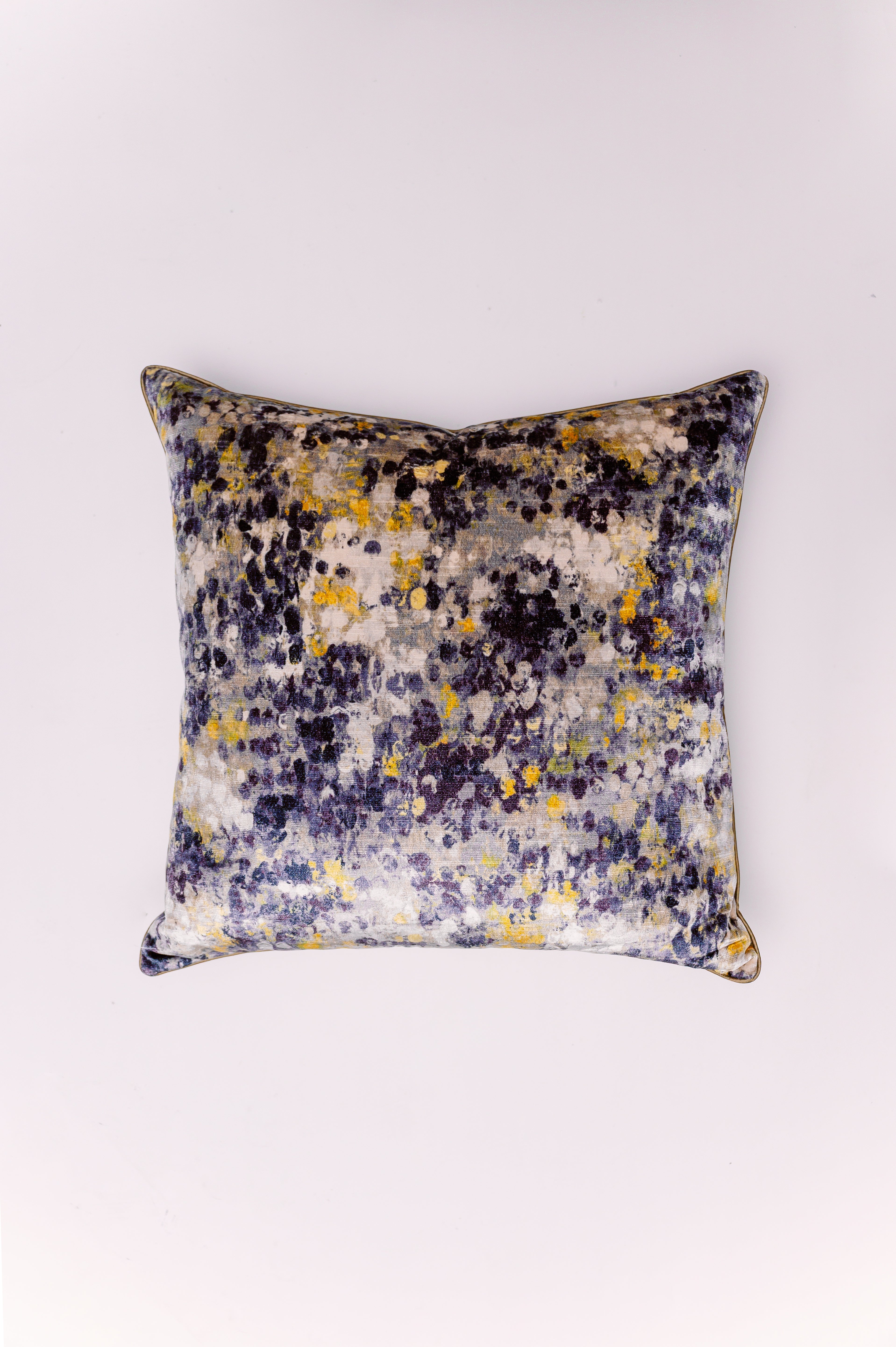 This luxurious pillow features a plush, shimmering velvet fabric with a dynamic, abstract watercolor print. The design is a lively convergence of colors, with deep navy, charcoal black, and splashes of sunny gold and soft gray. This painterly pattern resembles either an abstract splatter or a shower of glitter, giving it a sophisticated, energetic feel. The soft sheen of the velvet fabric enhances the depth of the colors, making it a perfect statement piece for contemporary, glam, or eclectic interiors.