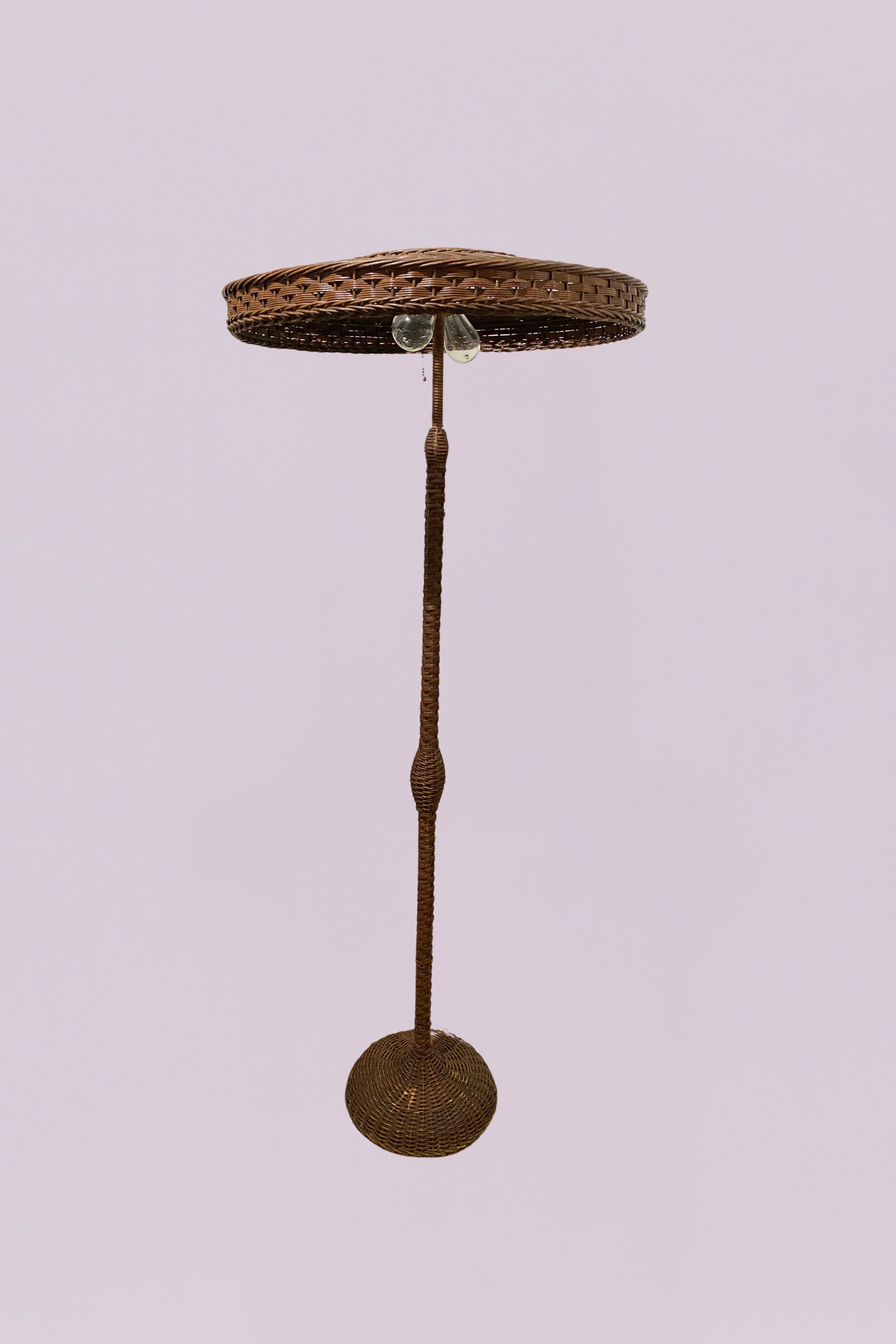 Vintage from the Florida, Everglades. This striking floor lamp features a complete woven rattan construction, embodying a warm, organic aesthetic typical of mid-century coastal and tropical designs. The piece is defined by its unique "parasol" or mushroom-style shade, which provides a wide, downward-dispersed light perfect for creating ambient atmosphere in a living space or sunroom.