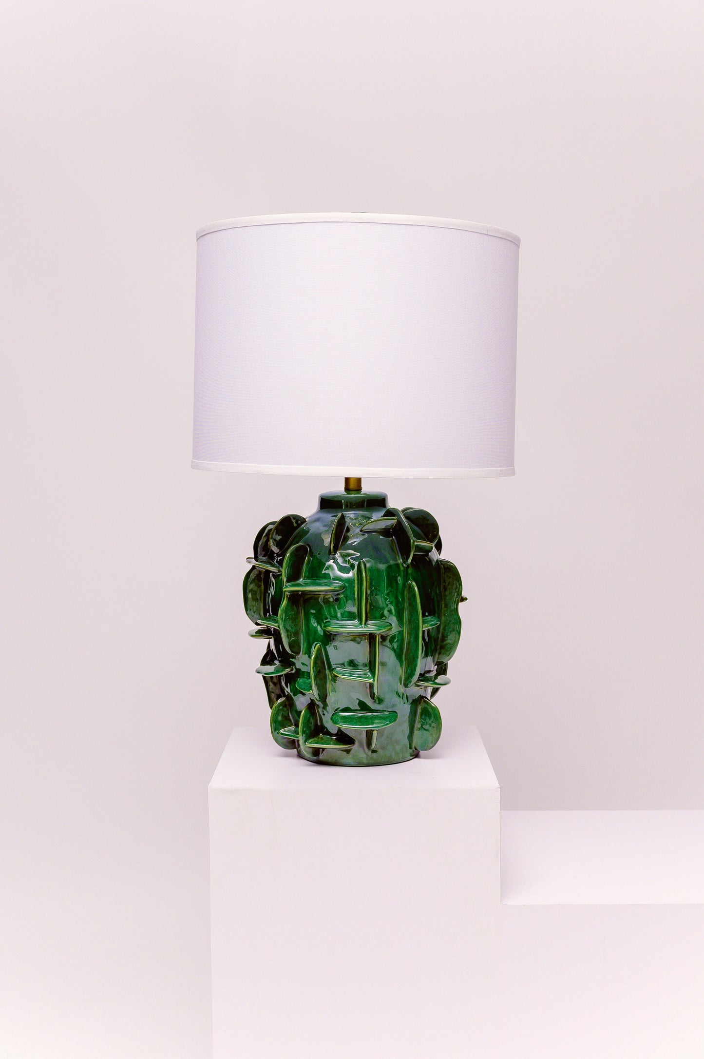 Green textured table lamp with a white shade on a white background