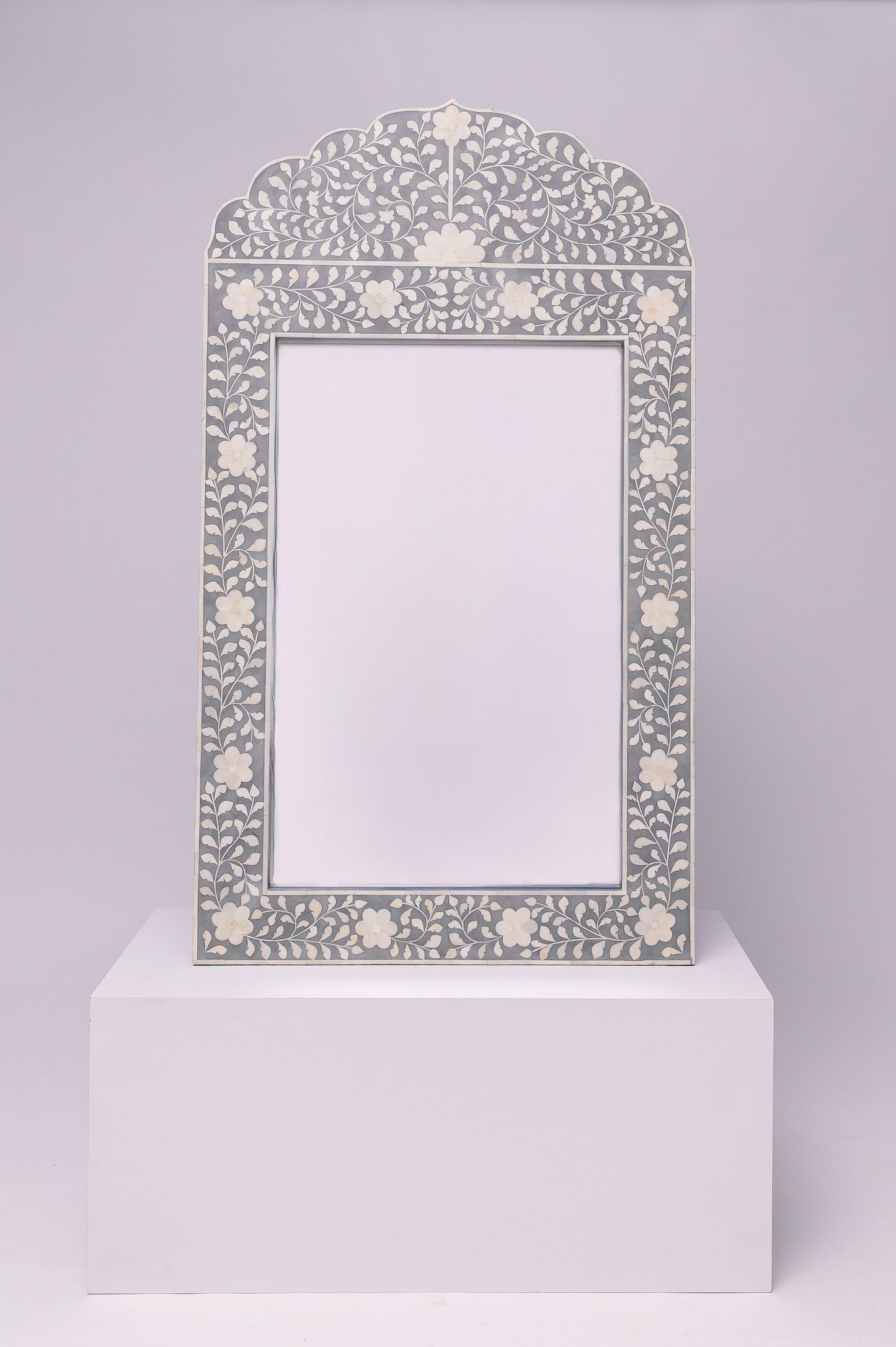 This mirror has an elegant, floral inlay with a soft scalloped arch that gives it a refined and timeless feel.