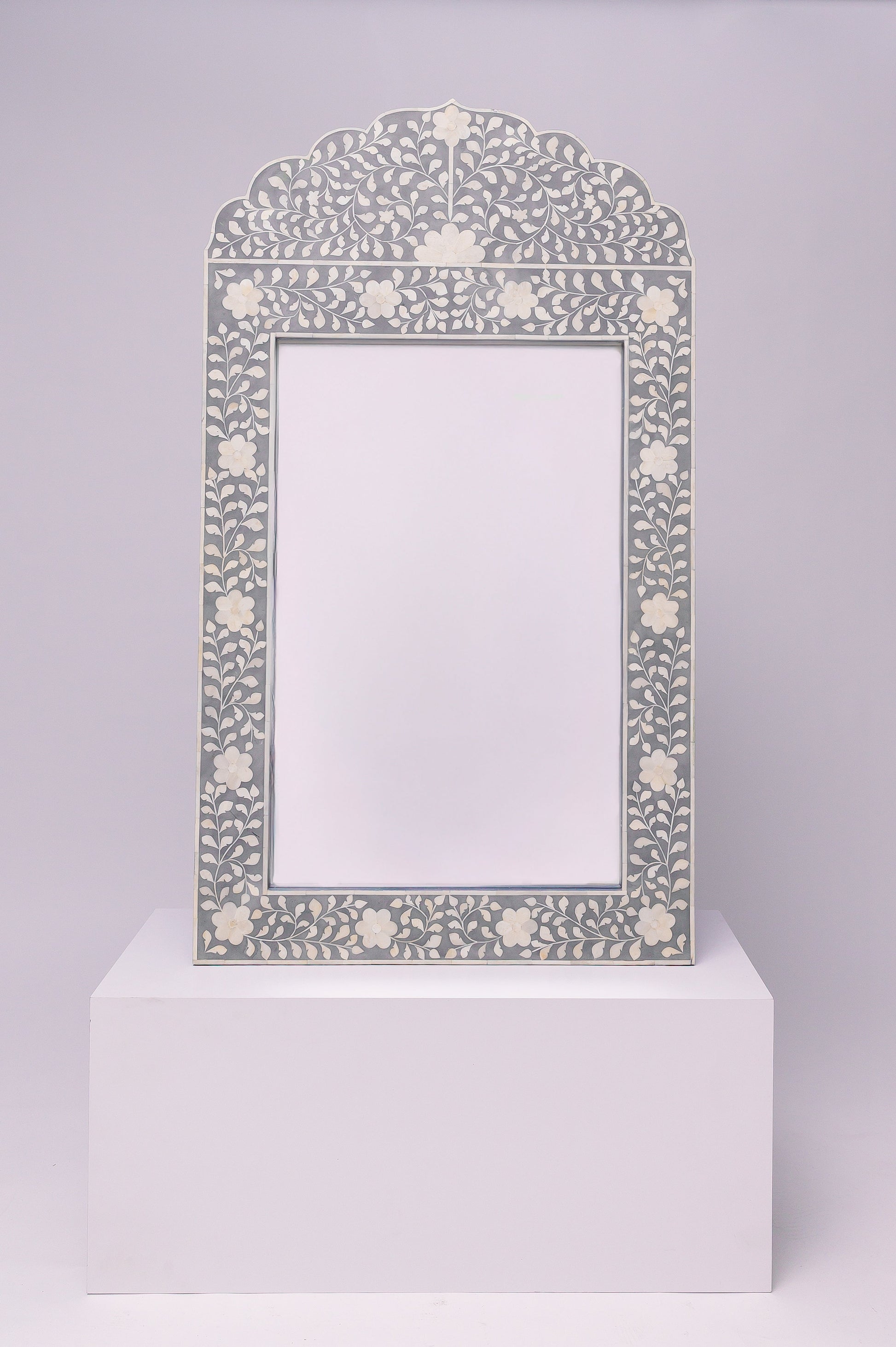 This mirror has an elegant, floral inlay with a soft scalloped arch that gives it a refined and timeless feel.