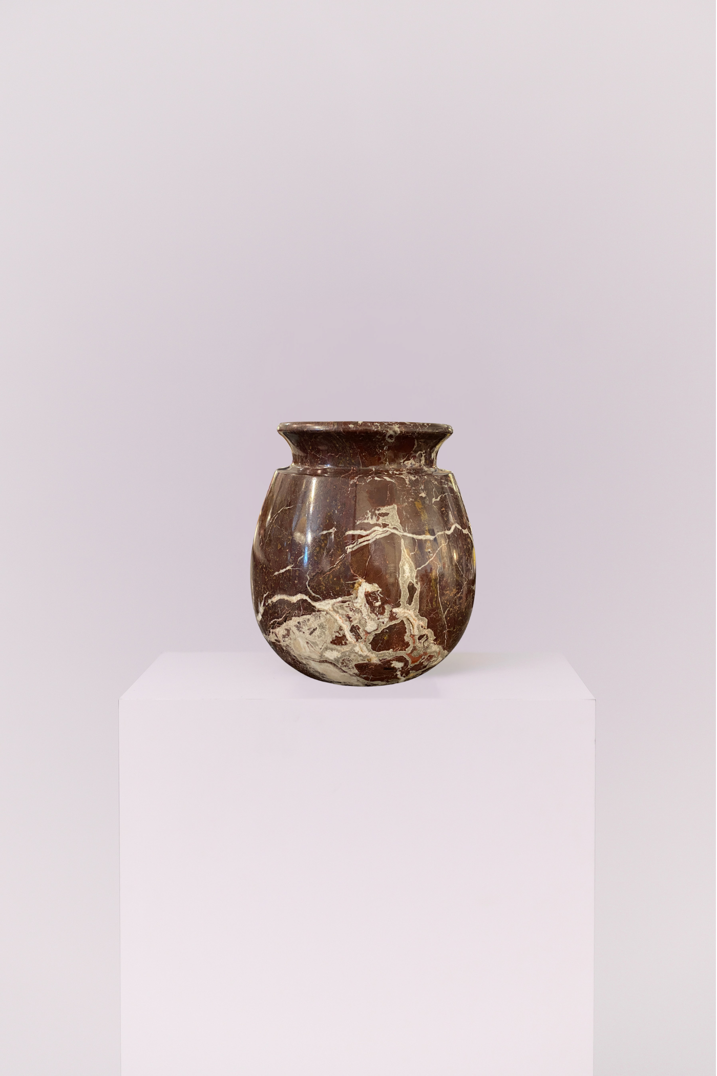 A heavy, small-scale stone vase featuring deep chocolate tones and dramatic white veining. Its rounded, classic silhouette brings a sense of weight and sophisticated history to any shelf or mantel.
