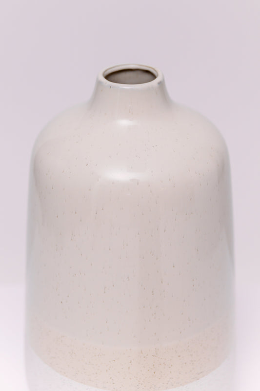 This minimalist stoneware vase features a clean cylindrical form with a soft taper at the neck. The body is finished in a natural two-tone glaze: a speckled white base, warm beige midsection, and soft taupe upper body, creating a subtle gradient effect. The matte texture and earthy palette lend a modern organic look, ideal for contemporary interiors.