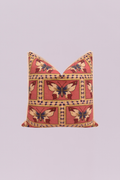 A beautifully rendered traditional-style pillow featuring repeating, framed motifs of majestic butterflies in deep red, navy blue, and cream on a rich, dusty rose background. The design is finished with a neutral, tailored flange edge, evoking an air of classic, vintage charm.