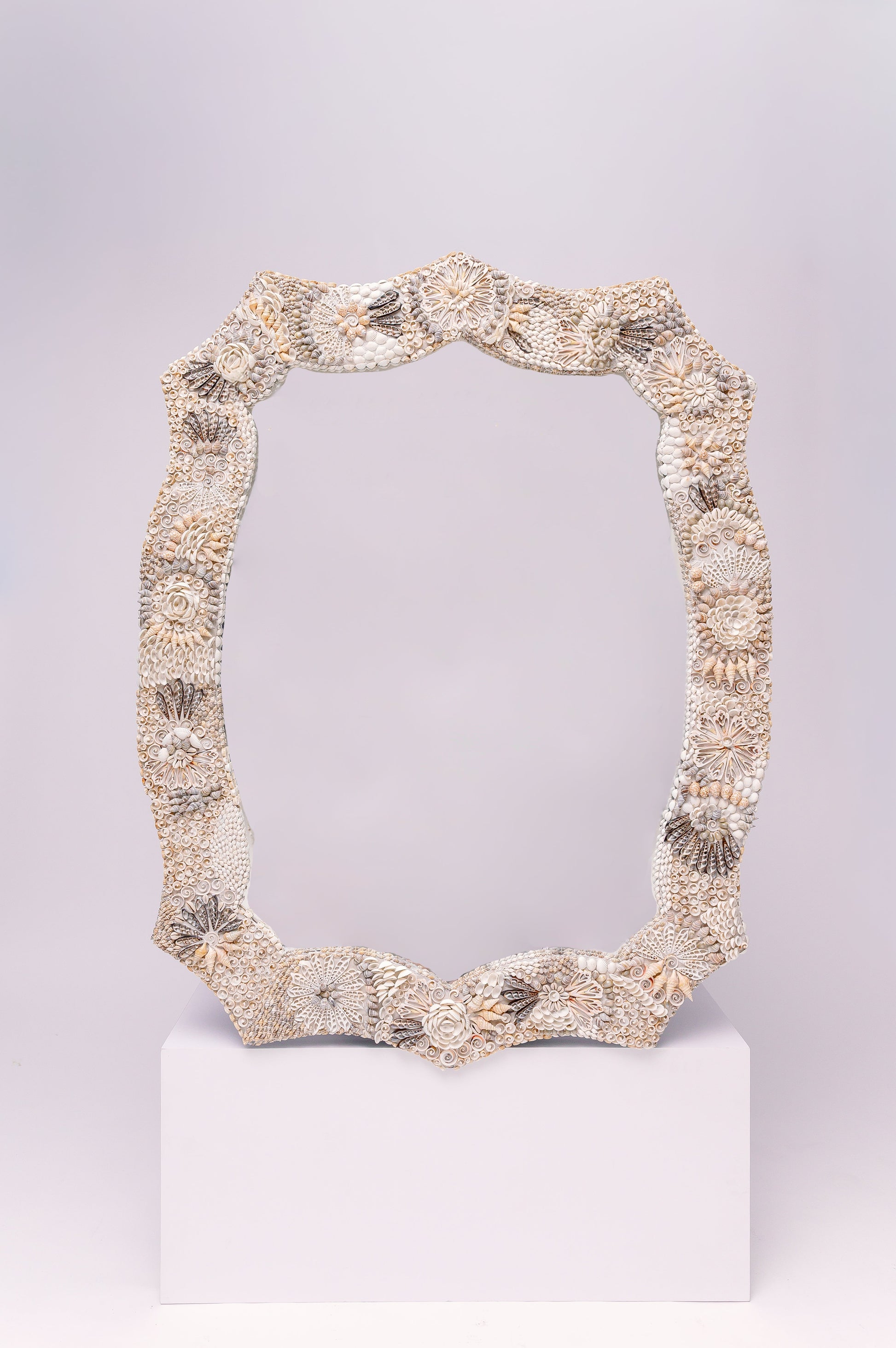 This  beautifully ornate mirror frame features intricate detailing made from seashells, arranged in floral and geometric patterns.