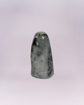 This is a smooth, free-standing accent piece cut and polished into a rounded, dome-topped obelisk or tower shape. A natural stone, featuring a blend of white, gray, and black speckling and veining.
