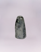 This is a smooth, free-standing accent piece cut and polished into a rounded, dome-topped obelisk or tower shape. A natural stone, featuring a blend of white, gray, and black speckling and veining.
