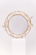 This mirror is an antique design with delicate metallic branches adorning the outside of the glass.