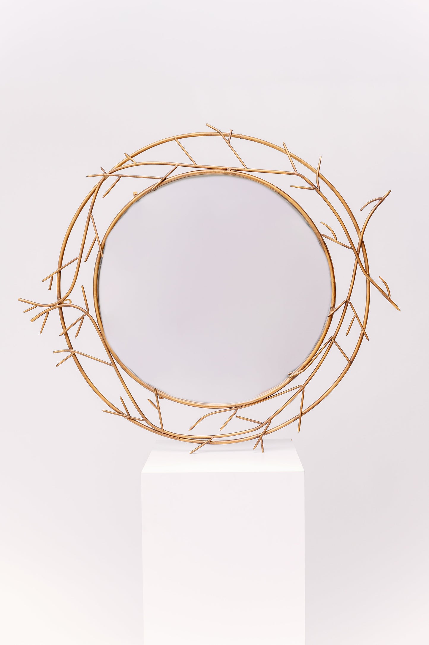 This mirror is an antique design with delicate metallic branches adorning the outside of the glass.