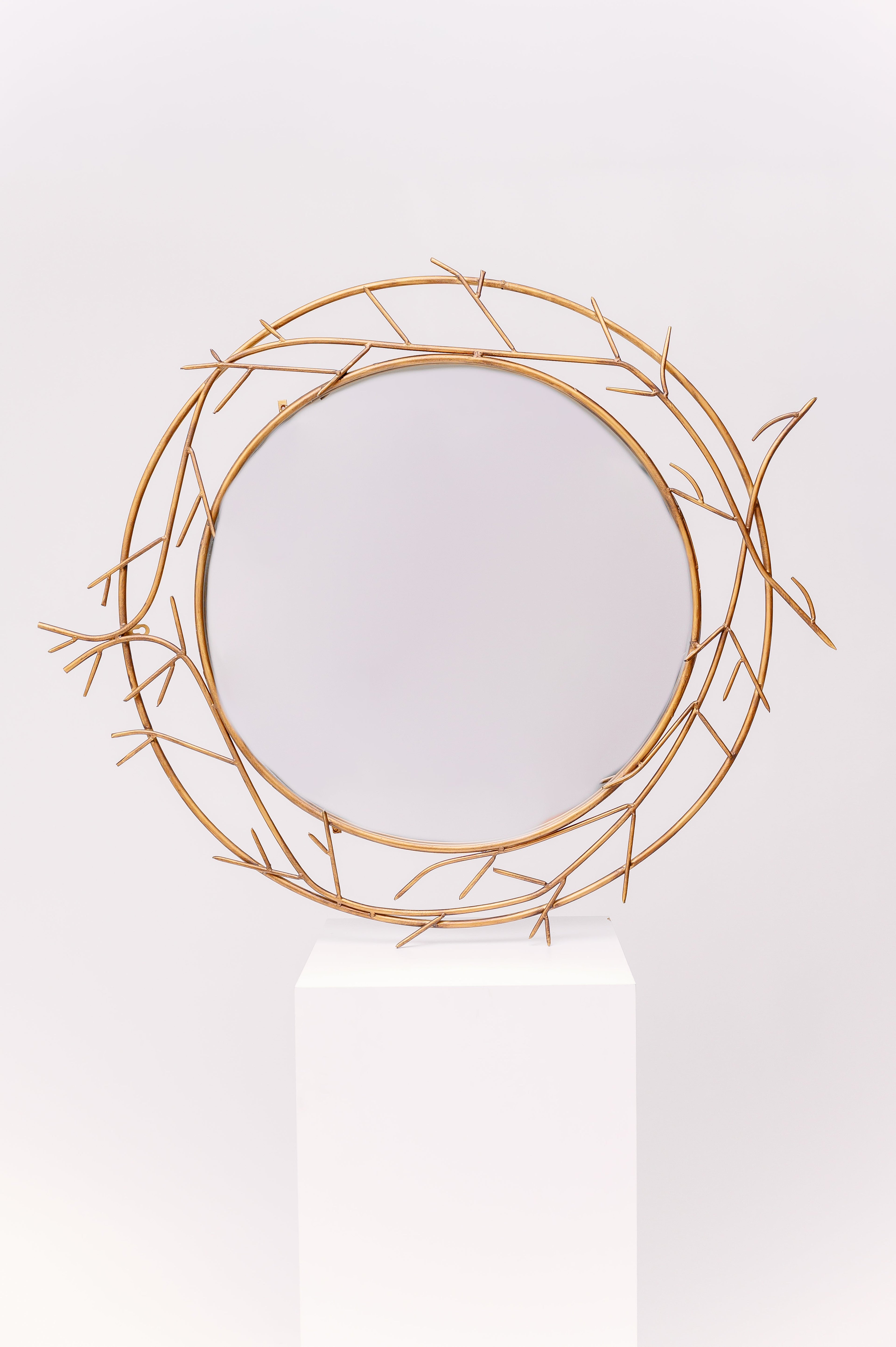 This mirror is an antique design with delicate metallic branches adorning the outside of the glass.