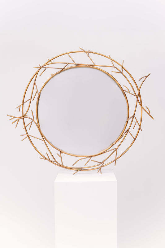 This mirror is an antique design with delicate metallic branches adorning the outside of the glass.