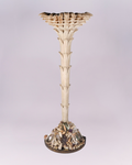 Carved wood palm tree Torchere attr. to Anthony Redmile has shell embelished base surmounted by carved wood form of a palm tree. Semi-circle metal base is covered with an assortment of sea shells in different shapes and sizes and measures 13"D x 22"W.  The tree form has wiring in the back and measures 74"H x 30"W top. 