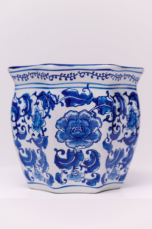 This square-form porcelain planter is hand-painted in underglaze cobalt blue, featuring scrolling peonies and stylized foliage. The peony, known as the “king of flowers,” is a traditional Chinese symbol of prosperity, honor, and wealth. The vessel’s gently flared rim and paneled body create a refined silhouette, while the continuous floral pattern enhances its decorative appeal.