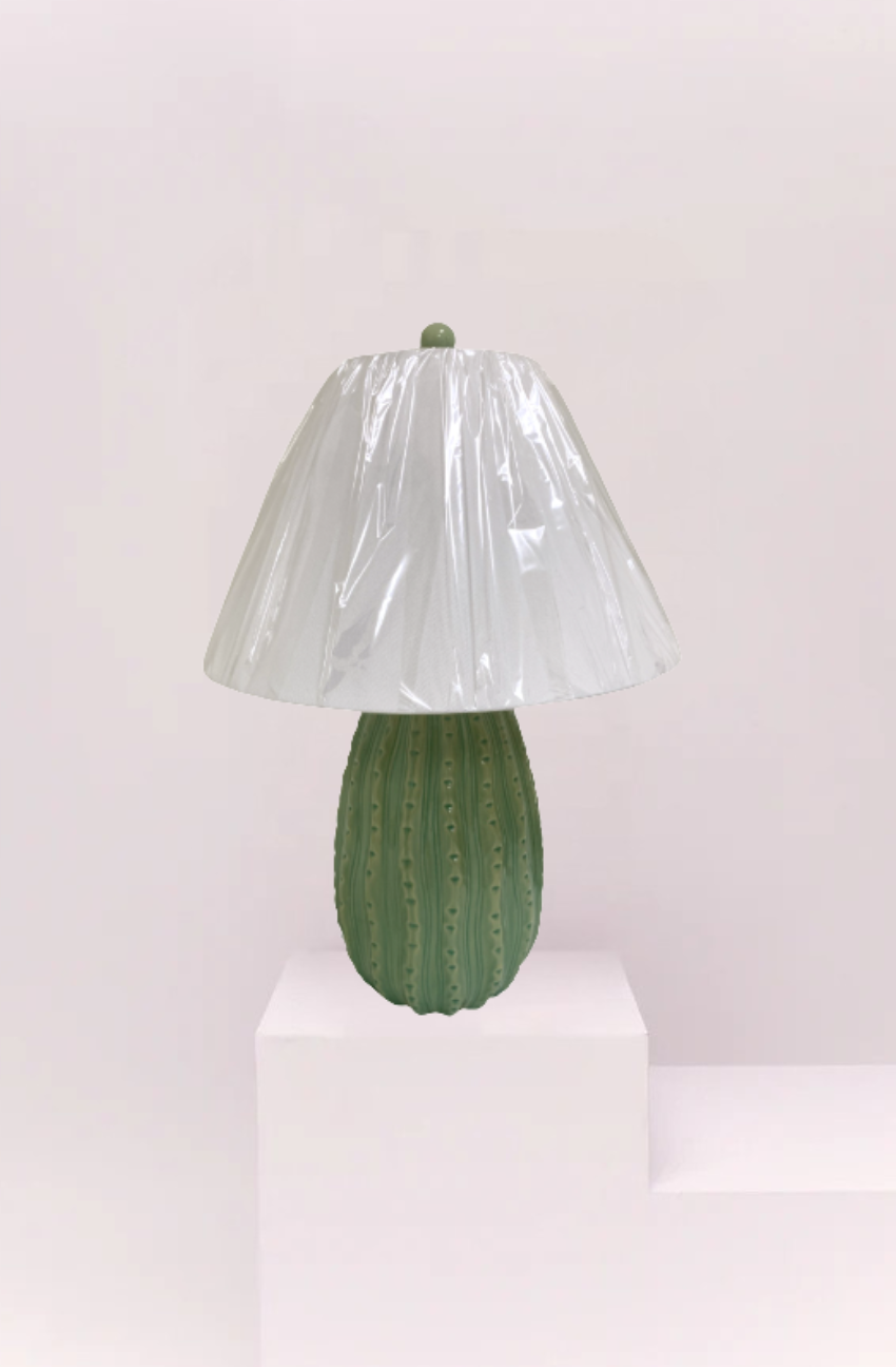 Cactus-shaped table lamp with a ribbed glass shade on a white pedestal against a light pink background