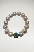 Experience the perfect harmony of classic opulence and vibrant, global elegance with this magnificent South Sea style statement bracelet. Composed of exceptionally large, luminous white cultured pearls, this piece is anchored by a breathtaking, artisanal focal turquoise bead and gold detail that introduces a captivating pop of color and texture.