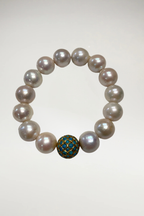 Experience the perfect harmony of classic opulence and vibrant, global elegance with this magnificent South Sea style statement bracelet. Composed of exceptionally large, luminous white cultured pearls, this piece is anchored by a breathtaking, artisanal focal turquoise bead and gold detail that introduces a captivating pop of color and texture.