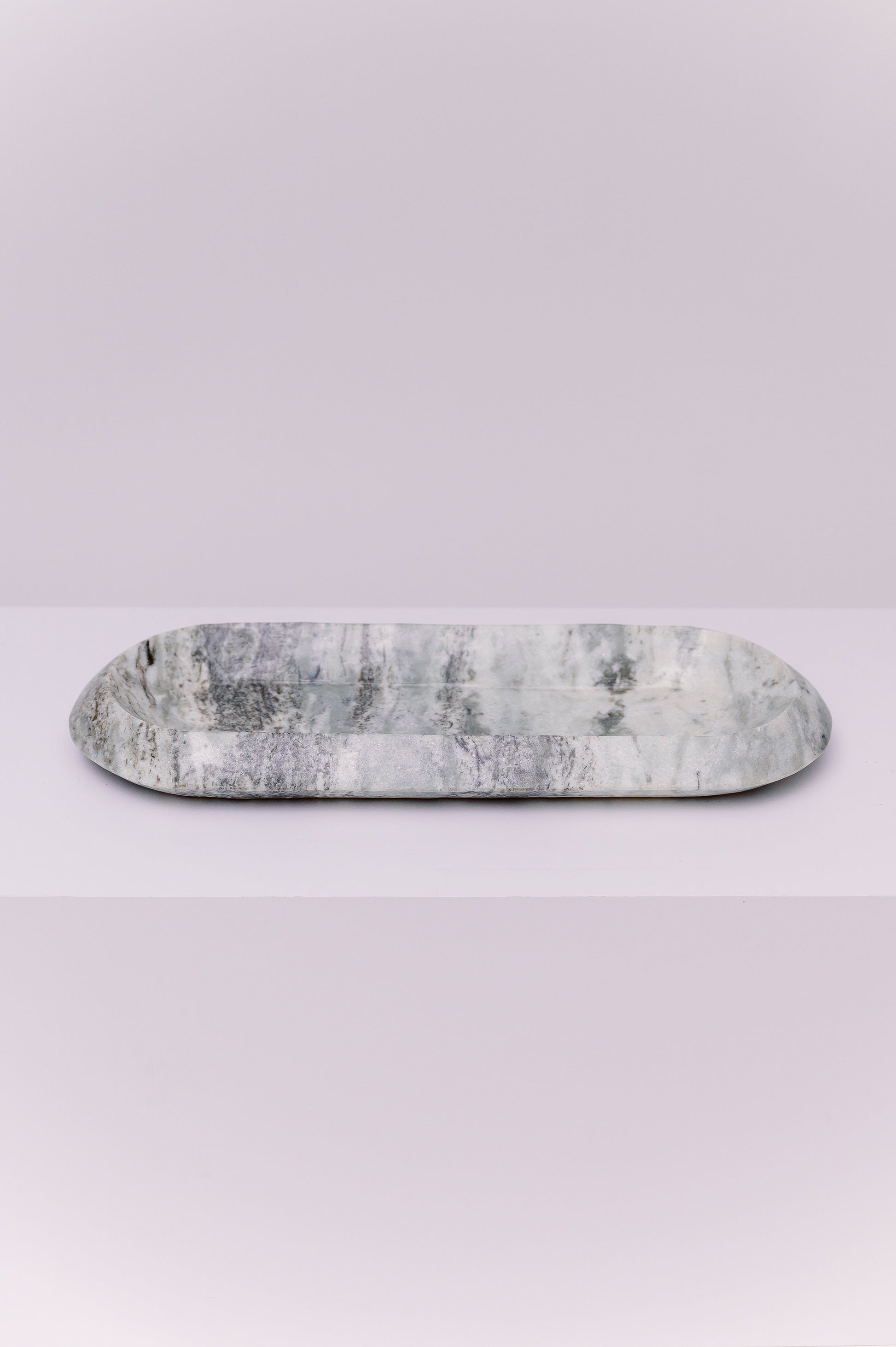 This exquisite oval tray is more than just an object; it is a whisper of history captured in stone. Carved from genuine marble, its luminous shades of grey and white swirl together in patterns as fluid as a river. This piece invites you to slow down, to feel its smooth, cool weight, and to find beauty in its natural veining. Let it become the anchor for your most cherished items—a tranquil home for your jewelry, a showcase for candles, or a stylish resting place for your daily essentials.