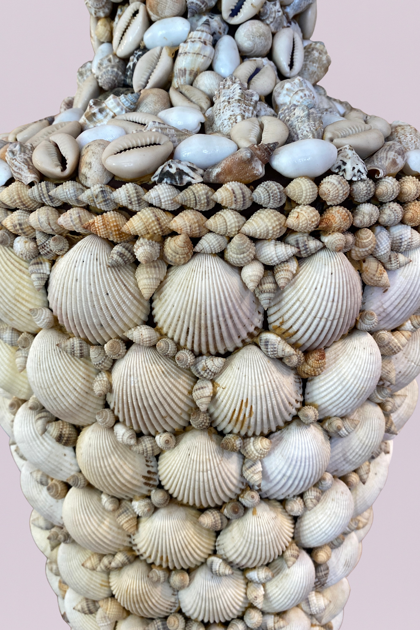 Decorative bust covered in seashells on a pink background