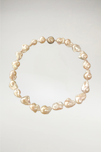 A majestic strand of oversized champagne baroque pearls. While The Eloise leans into cool, silvery-white tones, The Beatrice offers a warmer, more sun-kissed glow with deep honey and cream undertones. This piece is finished with a matching gold magnetic orb clasp to complement its rich, golden luster.