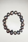 Embrace the striking beauty of imperfection with this captivating baroque pearl bracelet. Crafted from organically shaped, high-luster cultured pearls, this piece showcases a dramatic palette of deep charcoal, metallic silver, and iridescent oil-slick undertones.