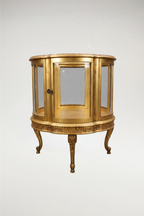 A sophisticated pair of  vintage circular display cabinets in the timeless Louis XVI style. Featuring a refined scalloped frame and a rich, aged-gilt finish, these vitrines offer an elegant, 360-degree view through seamless glass panels. Perfectly scaled for a moody, curated interior, they provide a regal stage for your most treasured collections