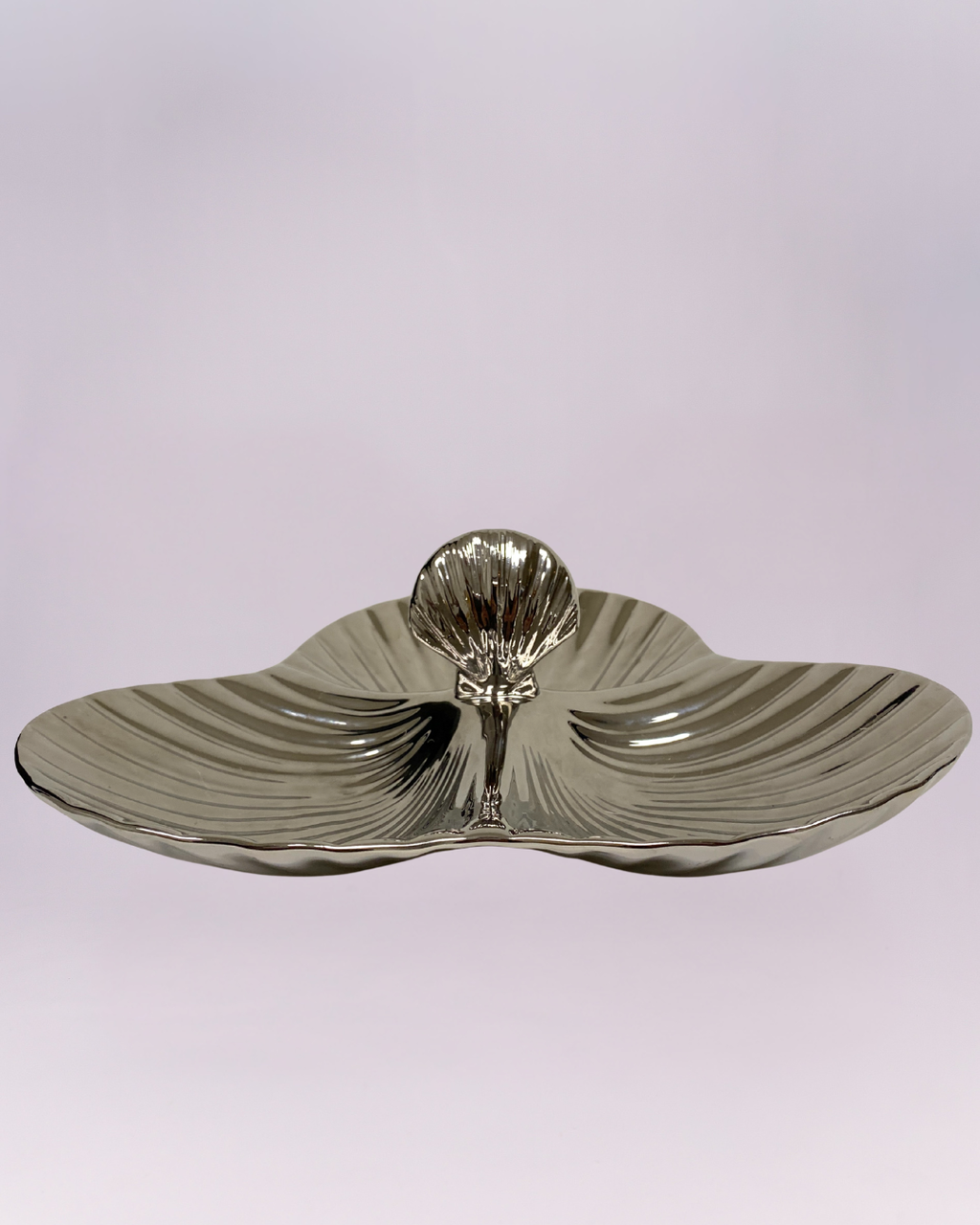 This is a highly reflective, three-section serving dish with a strikingly modern design. The piece features a triple-lobe, clover-like shape with a shallow central depression. The surface is heavily textured with a radial ripple or sunburst pattern, enhancing the metallic sheen of the material, which appears to be polished silver-toned metal or ceramic with a metallic glaze.