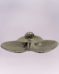 This is a highly reflective, three-section serving dish with a strikingly modern design. The piece features a triple-lobe, clover-like shape with a shallow central depression. The surface is heavily textured with a radial ripple or sunburst pattern, enhancing the metallic sheen of the material, which appears to be polished silver-toned metal or ceramic with a metallic glaze.