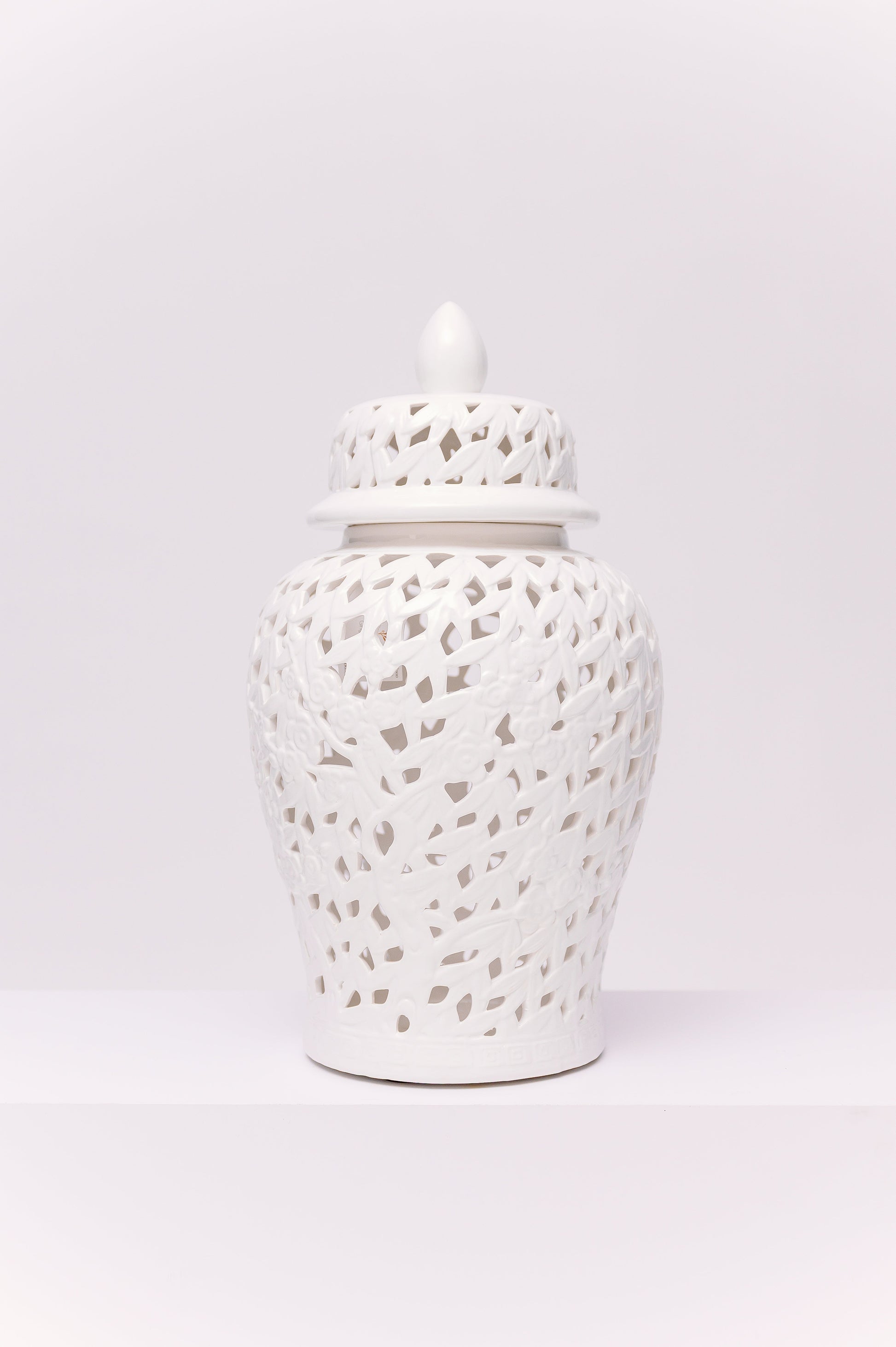 This elegant white porcelain ginger jar features a finely reticulated (pierced) lattice design, creating a delicate interplay of light and shadow. The body is adorned with sculpted floral and branch motifs worked seamlessly into the openwork pattern, adding depth and refinement. Topped with a domed lid and finial, the piece embodies a timeless chinoiserie aesthetic.