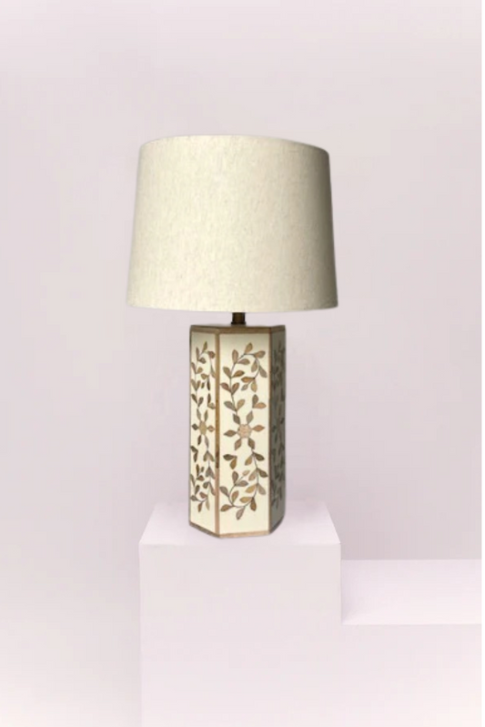 Table lamp with decorative base on a white pedestal against a gray wall